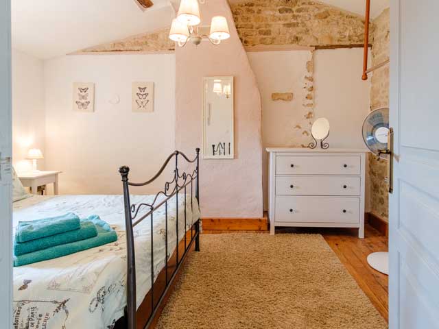 bright bedroom with light coloured walls and metal framed bed