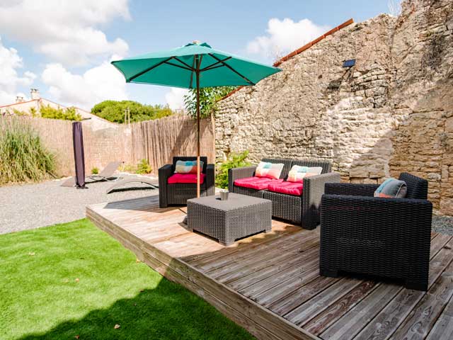 decked seating area with stone wall behind it and gravel area with sun loungers