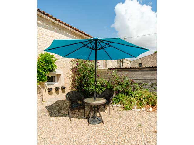 bistro table and two wicker chairs with blue sun umbrella