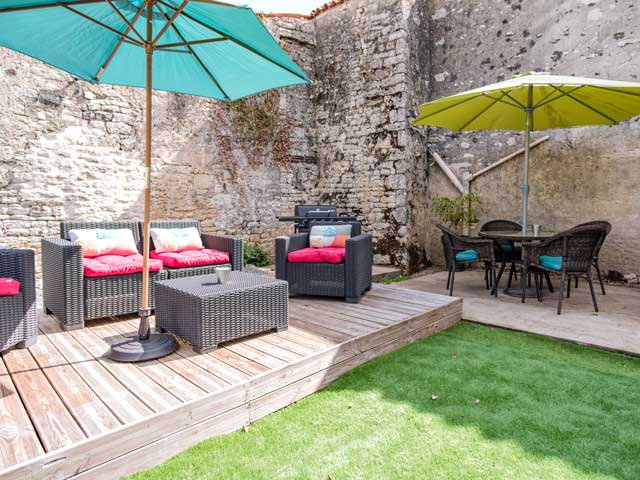 decked area with comfortable chairs with colourful cushions and two sun umbrellas