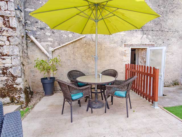 patio table and chairs with lime green umbrella in courtyard surrounded by stone walls