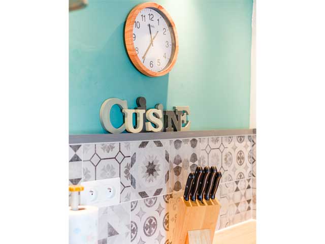 pale blue wall with a wooden wall clock and wooden letters spelling 'cuisine'
