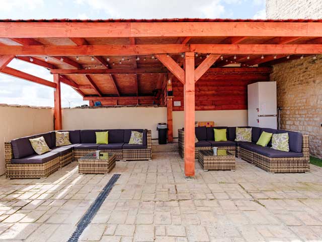 shadey outdoor seating area with a lot of comfortable wicker chairs and cushions
