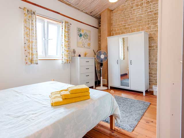 double bedroom with white furniture and open window letting in summer sunshine