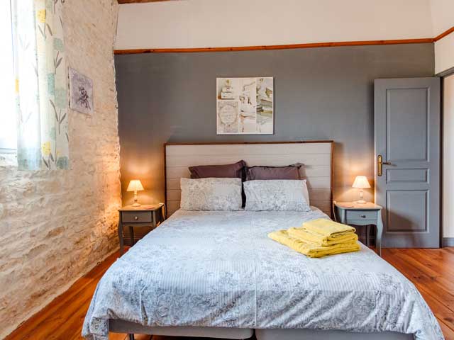 double bedroom with grey woodwork and furniture and light coloured stone wall and window
