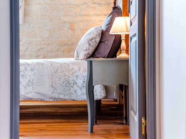 open door peaking into a bedroom with grey painted woodwork and side lamp