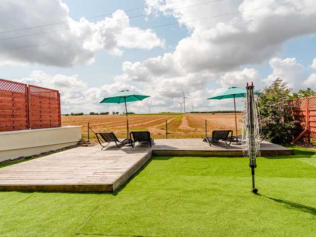 Decked area with sun loungers looking across the open French fields and windmills