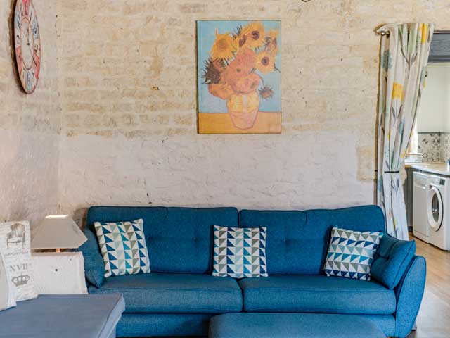 blue three-seater sofa with Van Gogh's sunflowers picture hanging on the stone wall