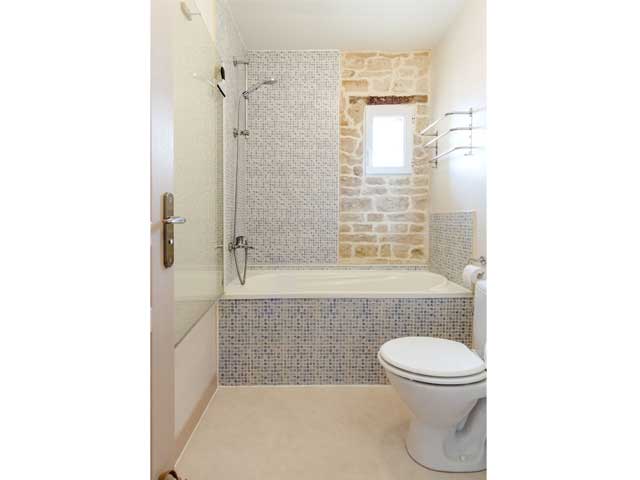 a bright and clean bathroom with toilet and bath/shower