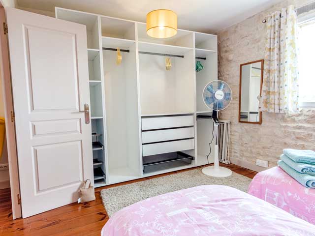 twin bedroom with lots of open clothes hanging space and free-standing fan