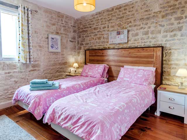 bedroom with twin beds and one large wooden headboard and pink duvet sets