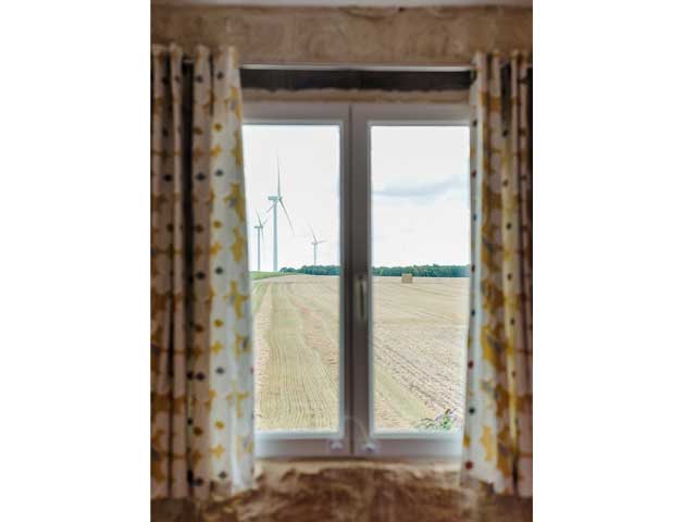 view out of the holiday accommodation window seeing the windmills, hay bails and open fields