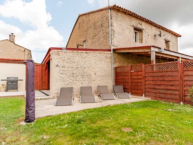 garden area with green grass and a tiled section with four sun loungers lined up neatly