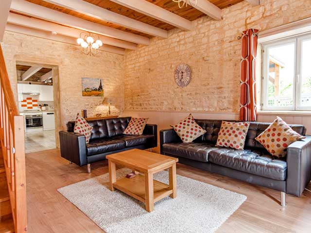 another view of the lounger area with leather sofas and open door to the kitchen area