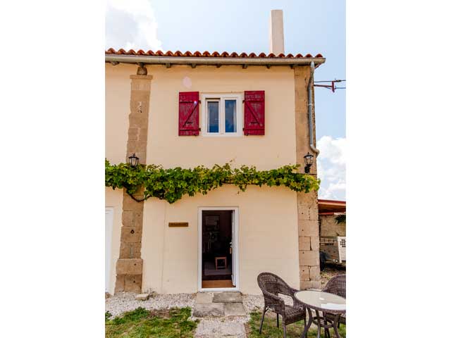 front of french attached gites showing holiday accommodation with red shutters and open door.